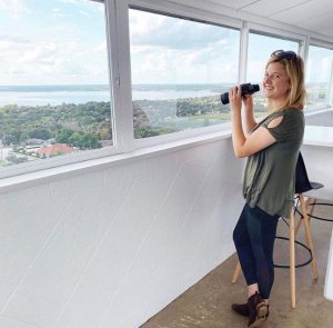 A woman holds binoculars and looks out at the top of the Florida Citrus Tower in Clermont, FL.