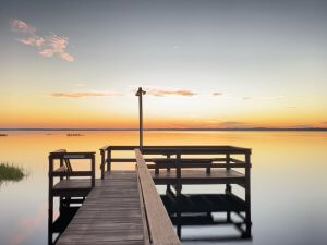 Photo of a pier on a lake at sunrise.