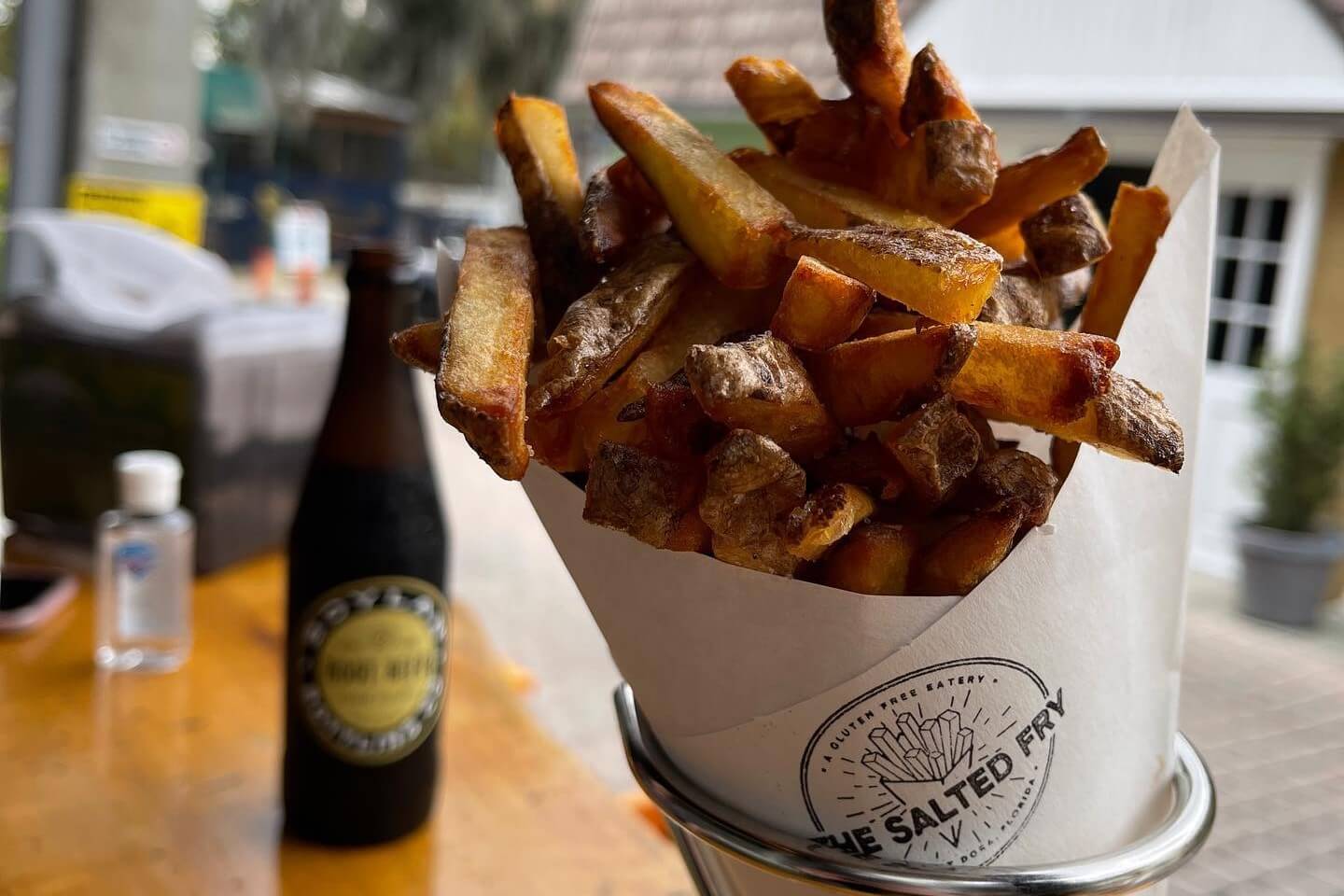 Photo of fries wrapped in a paper container sitting on a table.