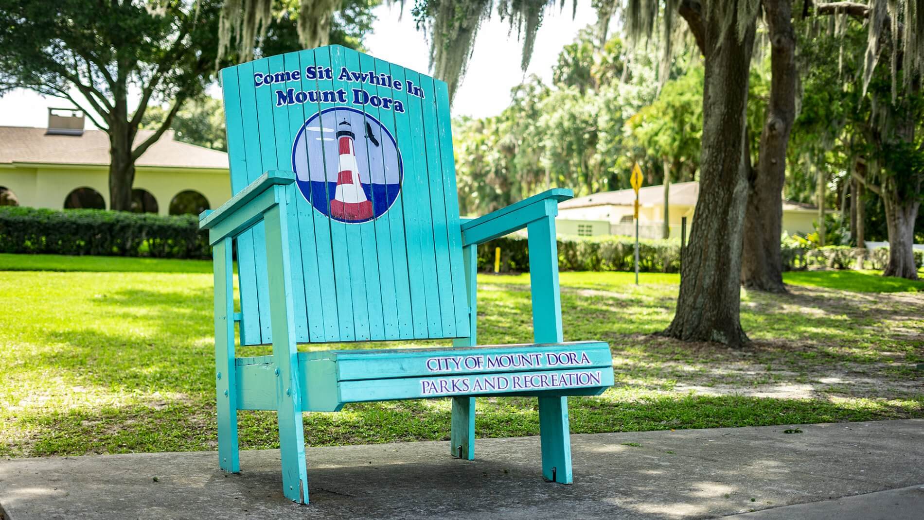 Photo of a big wooden chair that reads: "Come sit awhile in Mount Dora."